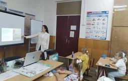 На изображении педагог рассказывает детям о истории празднике "День народного единства". На презентации на доске изображены орнаменты народов России.
