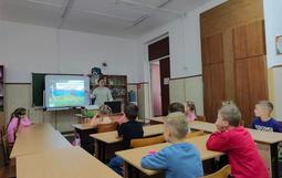 В кабинете дети сидят за партами. На стене экран с надписью "День народного единства" дети внимательно слушают педагога.