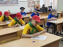 В классе дети в жёлтых футболках и красных кепках пишут тест. 