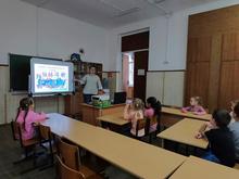 ёВ кабинете дети сидят за партами. На стене экран с изображением карты, на которой отмечены места проживания разных народов дети внимательно слушают педагога.
