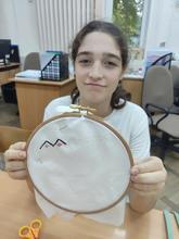 Ребенок держит пяльцы с вышивкой в виде орнамента